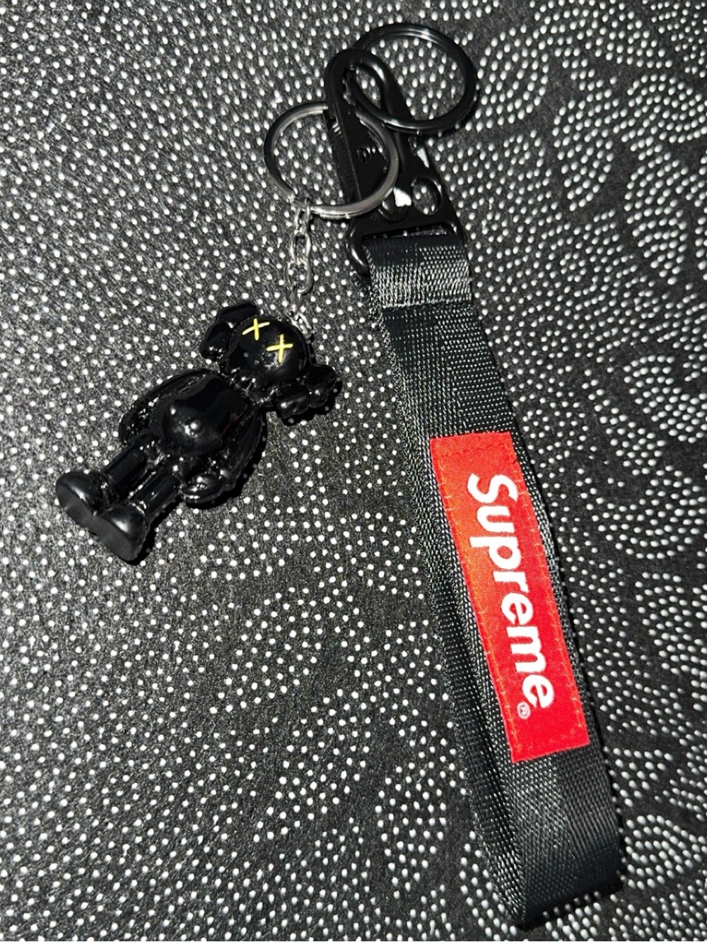 Supreme Black Strap Keychain with Black Figure Charm and Red Logo